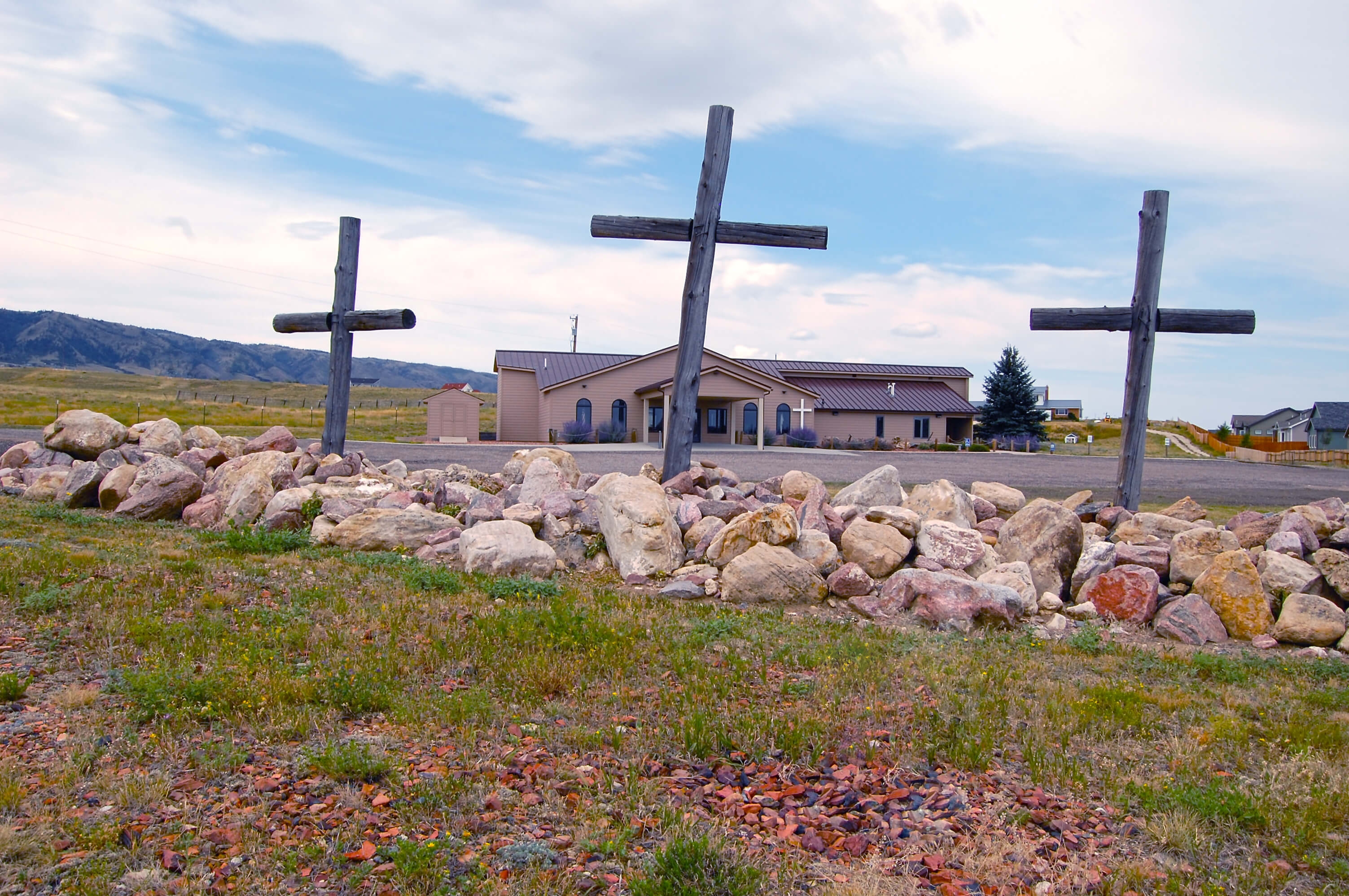 A picture of the exterior of the church looking through the three crosses that are in the front of the building